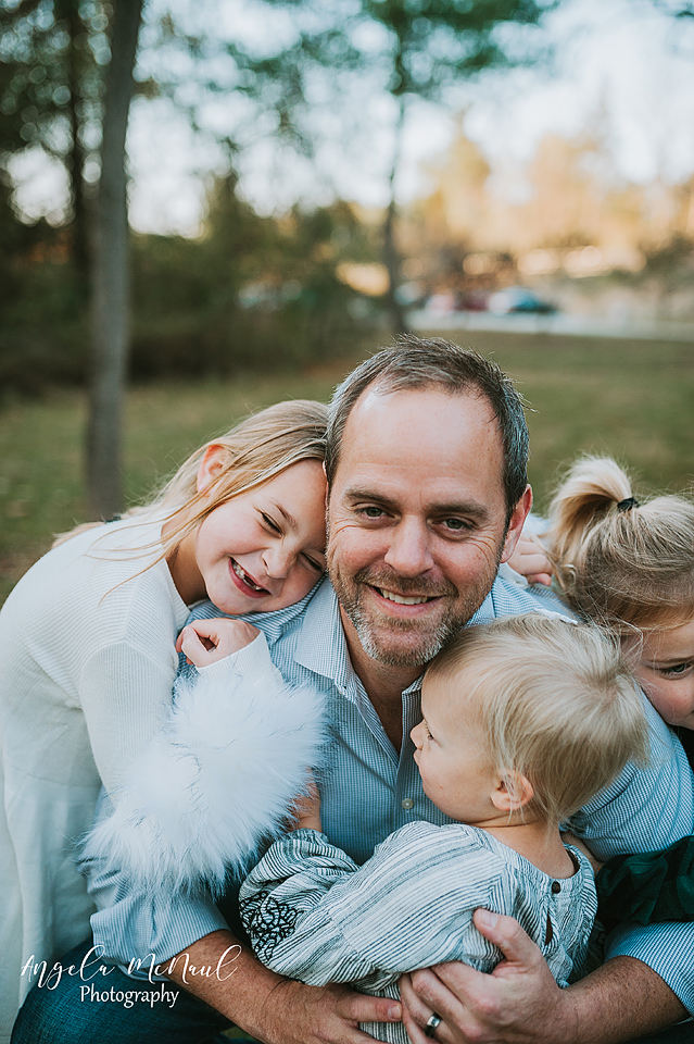 A lifestyle family session with three girls hugging their dad