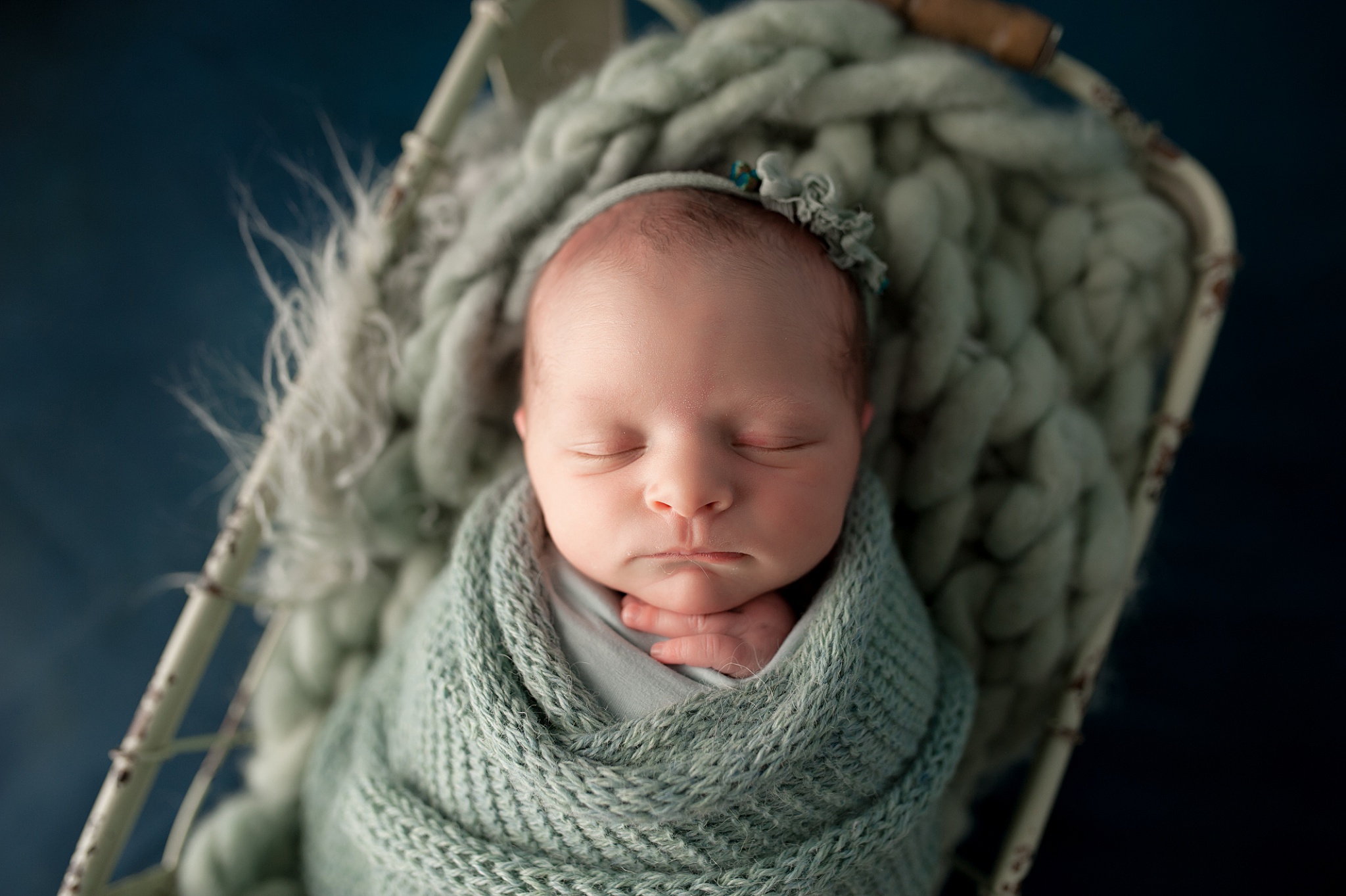 newborn swaddled with hands sticking out wrapped in green wrap