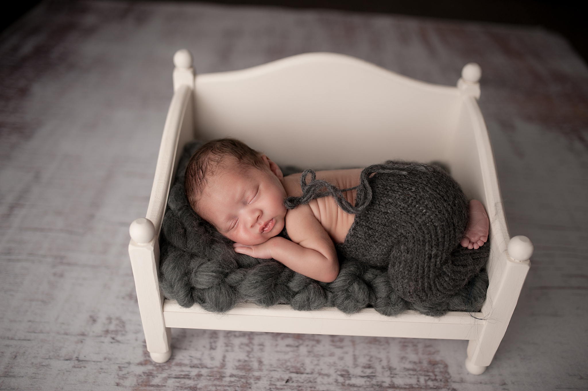 newborn baby on white wooden bed