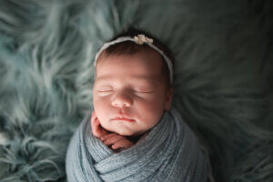 Newborn Baby in Blue Swaddle Wrap Photography by Angela McNaul