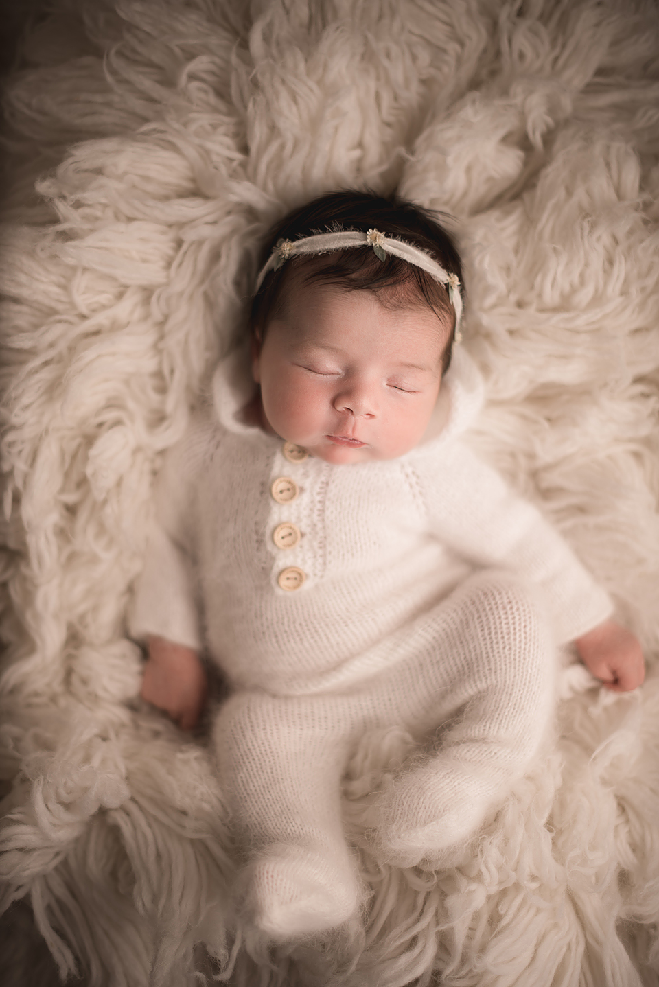 Sleeping Newborn Girl Wearing White Pajamas and Headband