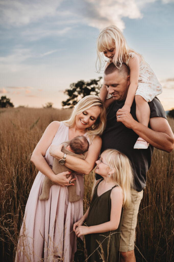 a family of 5 with a newborn baby bonding in a field in Old Trail Crozet.