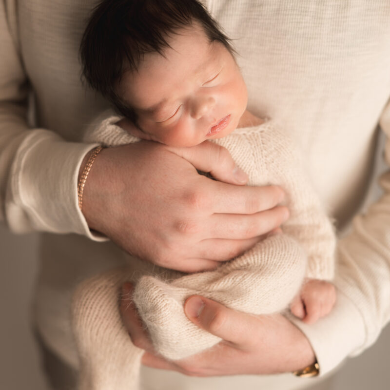 Dad holding his newborn baby in his arms