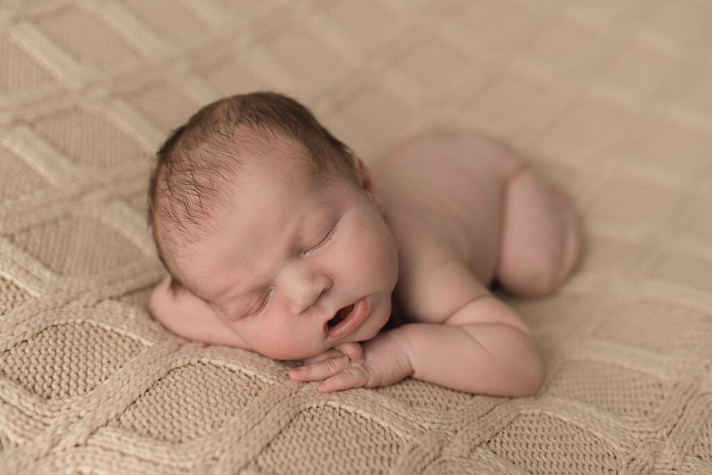 sleeping newborn baby laying on a cream colored knit blanket, sleeping