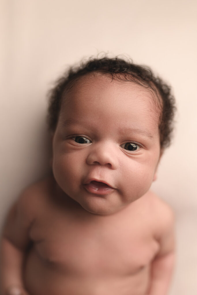 African American baby with curly hair making eye contact with the camera