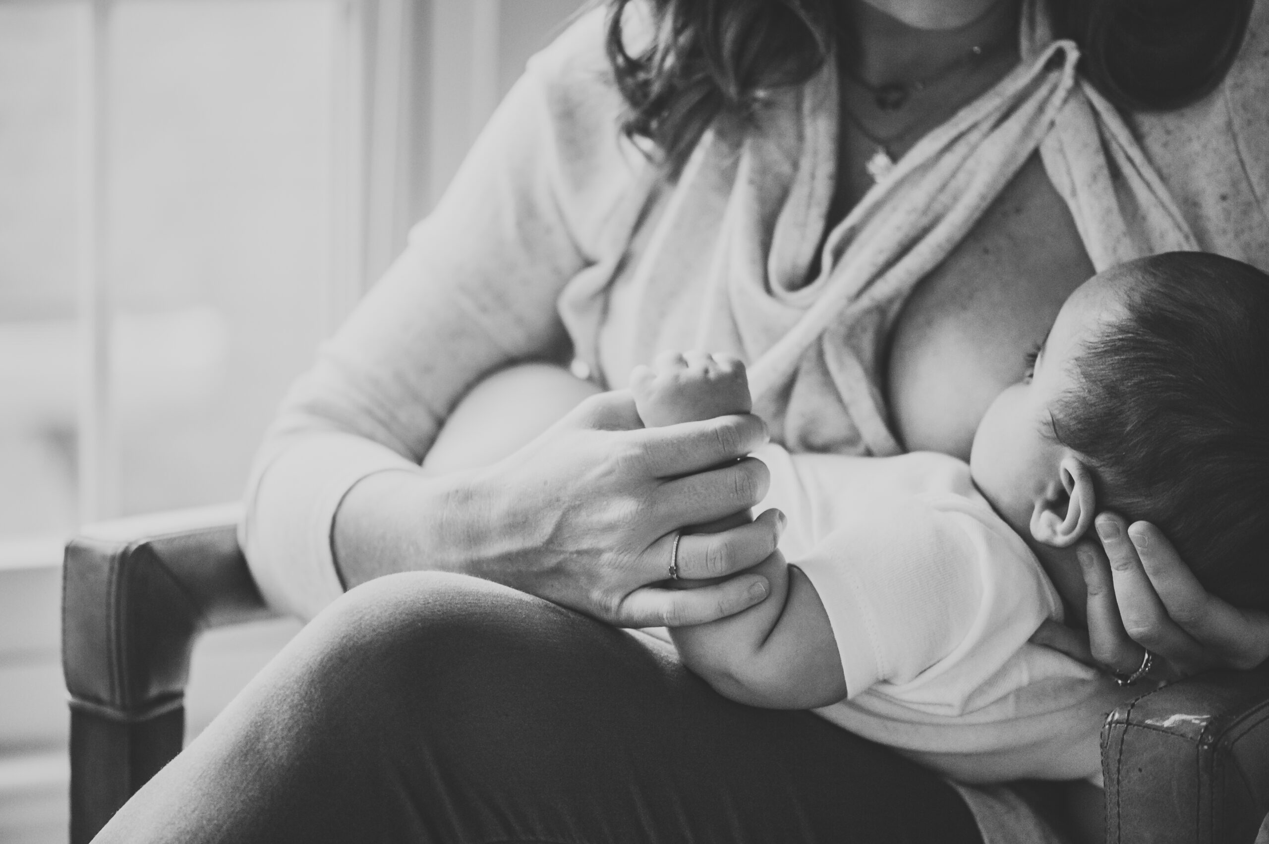 Mom holding her baby's hand while he is breastfeeding