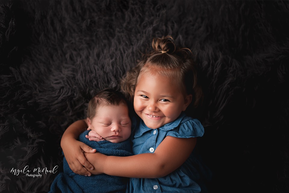 Toddler Girl laying next to her baby sibling