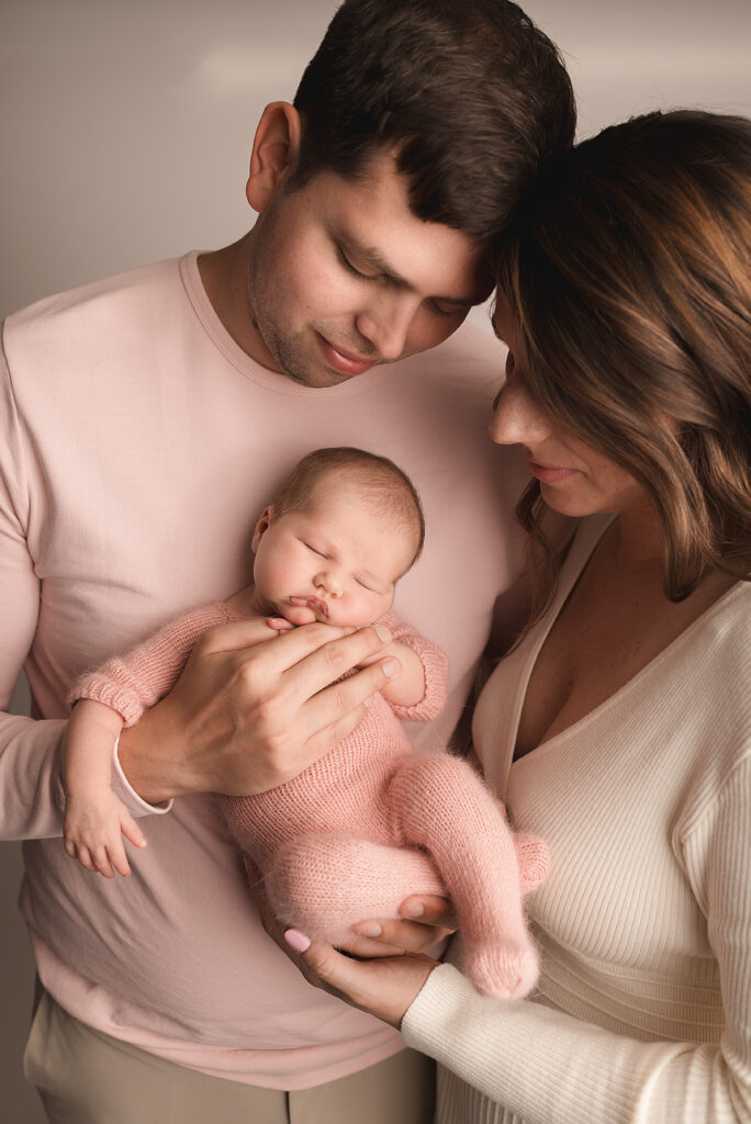 Newborn family portrait in Charlottesville studio with parents holding swaddled baby girl